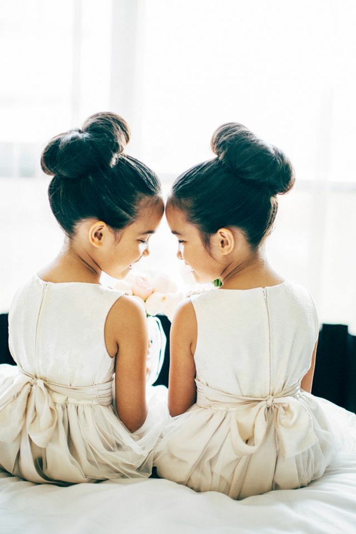 eineiige-zwillinge-mit-eleganten-frisuren-und-weißen-kleidern