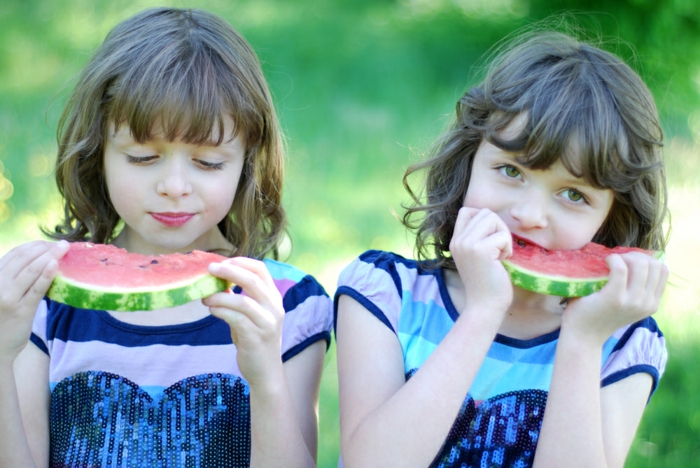 eineiige-zwillinge-zwei-süße-mädchen-essen-wassermelone