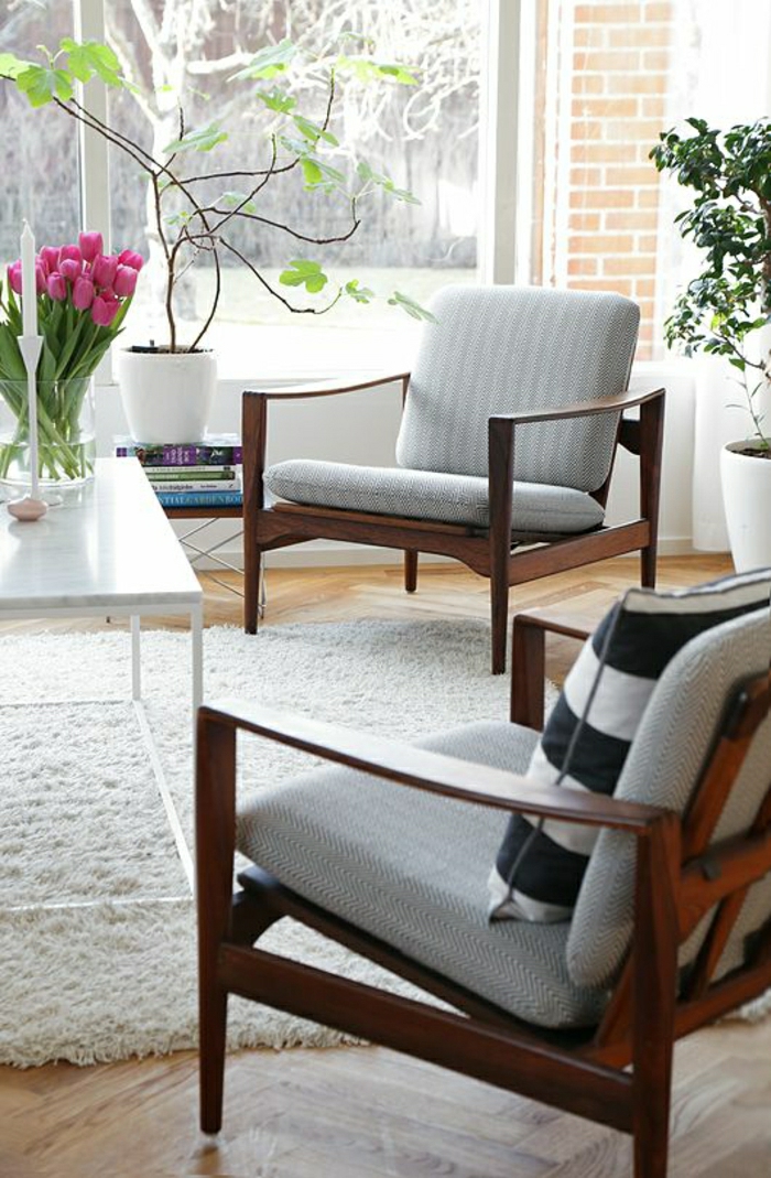 Wohnzimmer-skandinavisches-Design-flaumiger-Teppich-altmodische-Stühle-gestreifte-Kisse-Bücher-Blumentöpfe-rosa-Tulpen-Kerzenhalter