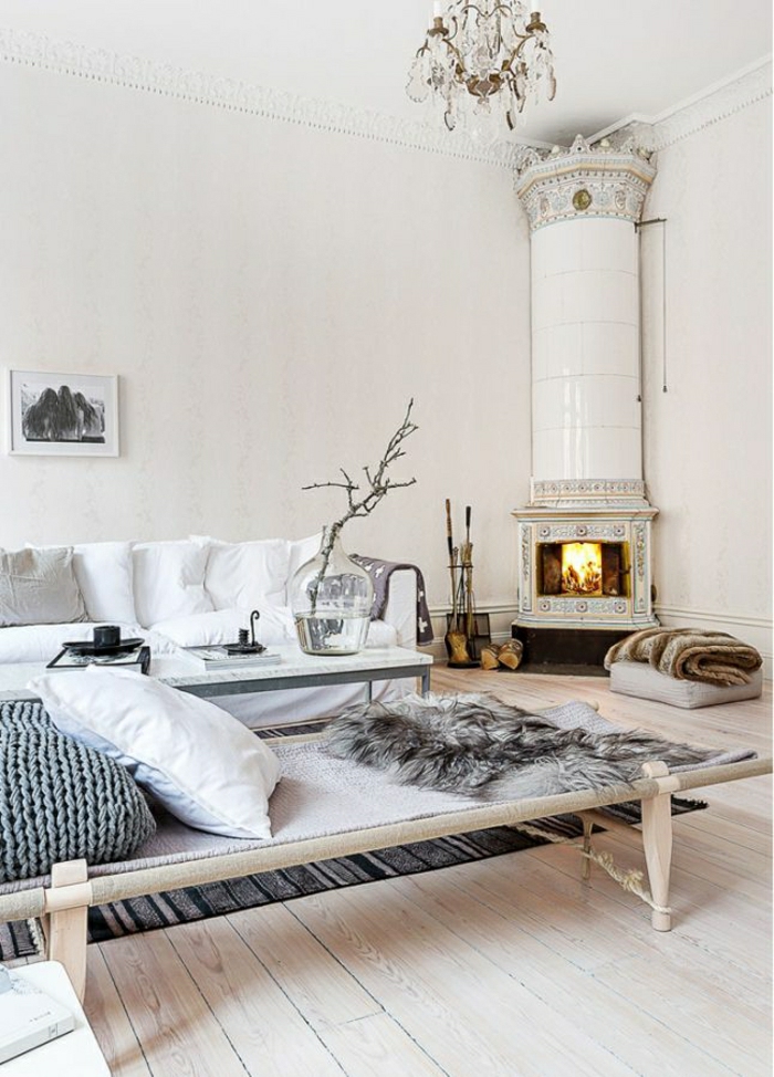 Wohnzimmer-skandinavisch-weiß-Kamin-Sofa-Brennhölzer-Schlafdecken-Kronleuchter