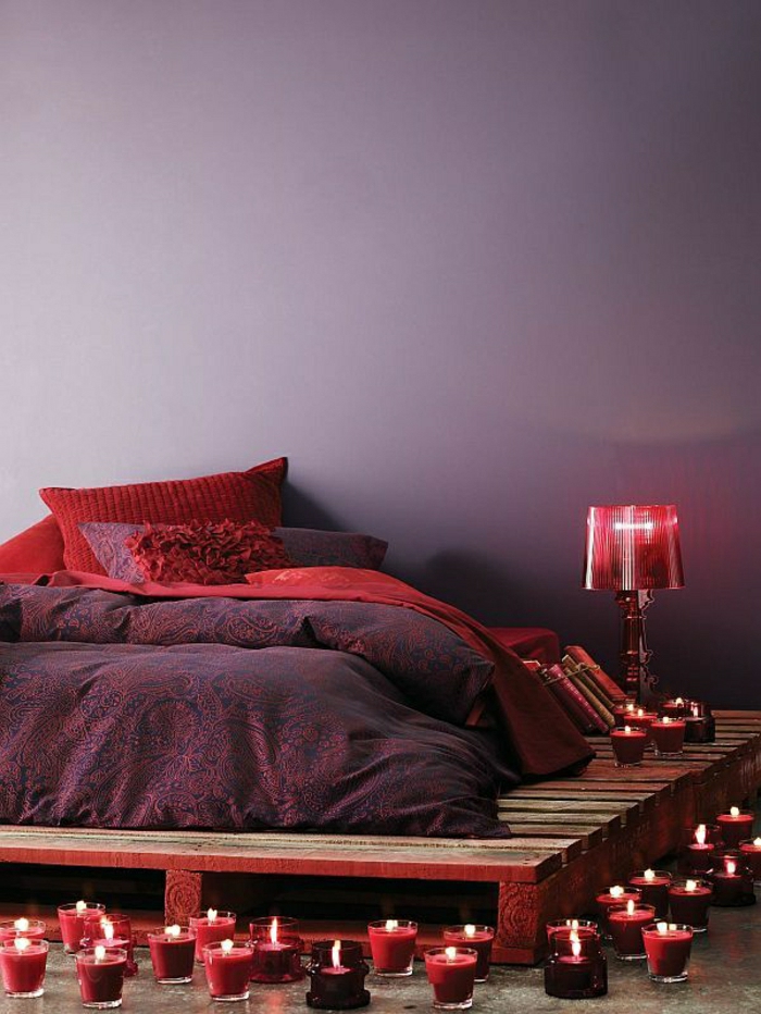 exotisches-Schlafzimmer-lila-Wände-Bettwäsche-rot-lila-Ornamente-Kissen-Palettenbett-rote-Lampe-Kerzen