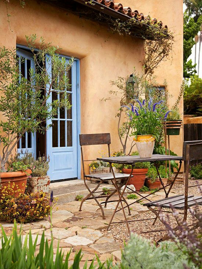 mediterrane-Gartengestaltung-Tisch-Stühle-Schmiedeeisen-Blumentopf-blaue-Tür
