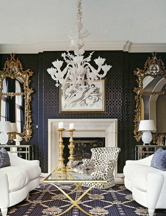 reich-dekoriertes-Barock-Wohnzimmer-Kronleuchter-graphischer-Sessel-Spiegel-goldene-Elemente-weiße-Sofas-Kamin-massive-Kerzenhalter