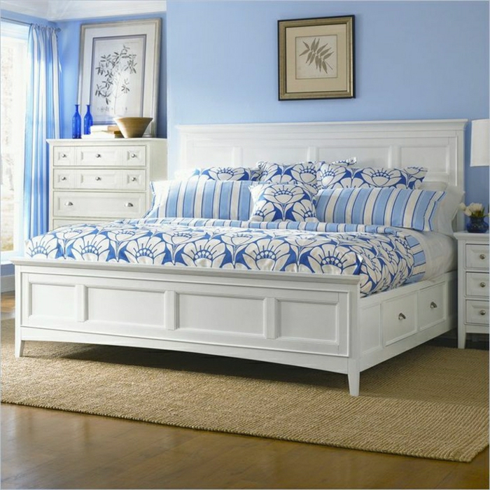 Schlafzimmer-weißes-Bett-Schubladen-blaue-Bettwäsche-Ornamente-Nachttisch-Kommode-Rattan-Teppich-blaue-Wände-Gardinen