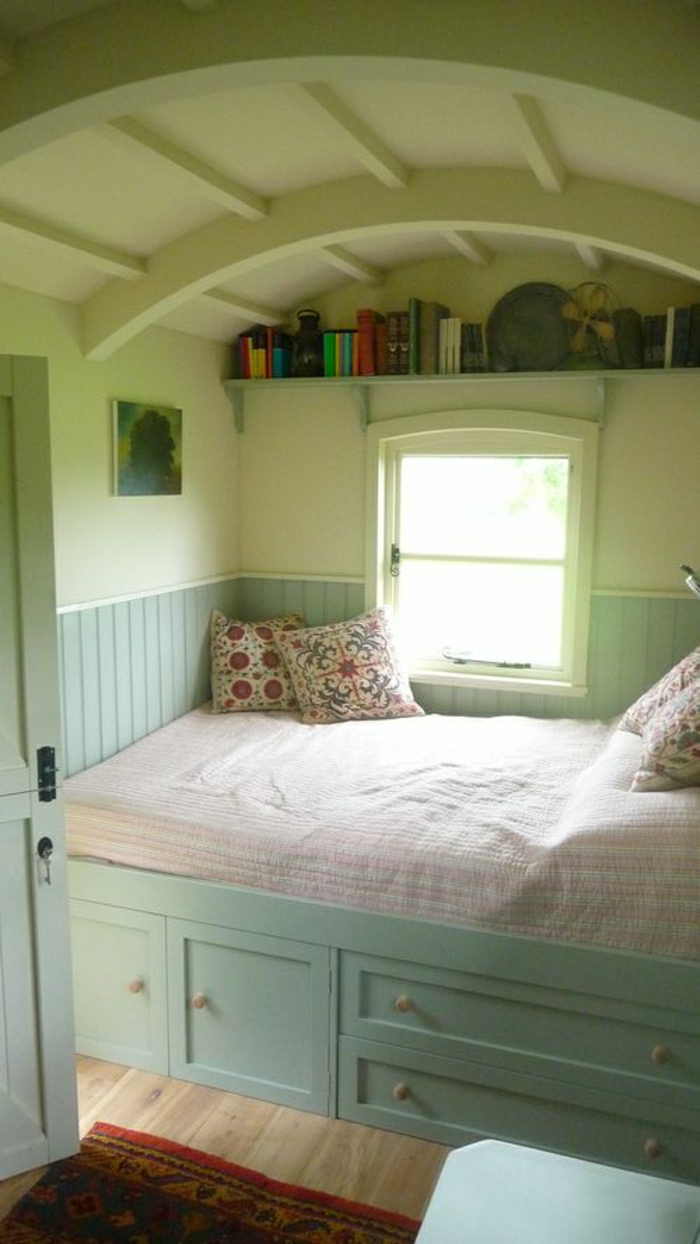 grünes-Schlafzimmer-Bett-Minze-Farbe-Schubladen-bunte-Kissen-Bücherregal