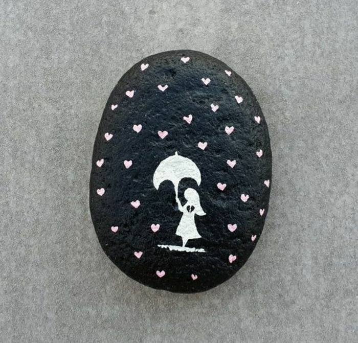 handgemalter-Stein-schwarze-Grundlage-weiße-Zeichnung-kleines-Mädchen-Regenschirm-Regentropfen-Herzen