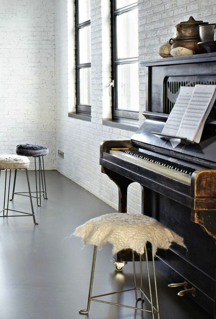 moderne-Wohnung-weiße-Ziegelwände-altes-vintage-Klavier-drei-Hocker-Notenblätter