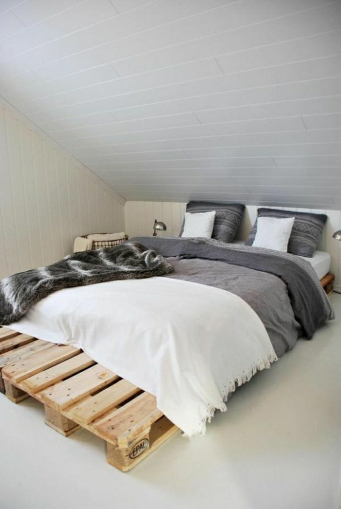 Dachwohnung-minimalistisches-Interieur-europaletten-bett-graue-Bettwäsche-weiße-Schlafdecke