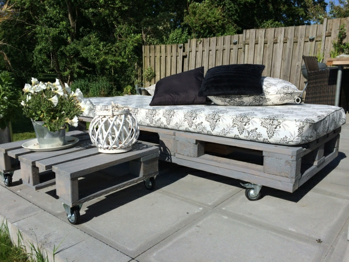Patio-Gestaltung-graue-Palettenmöbel-Rollen-schöne-Matraze-schwarze-Kissen-Blumen