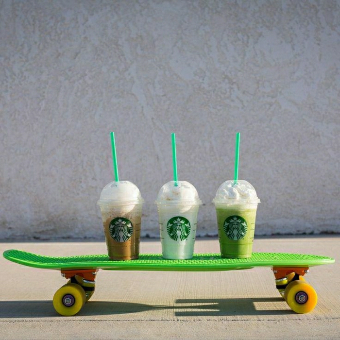 drei-Starbucks-Becher-verschiedene-Getränke-Strohe-Rollbrett