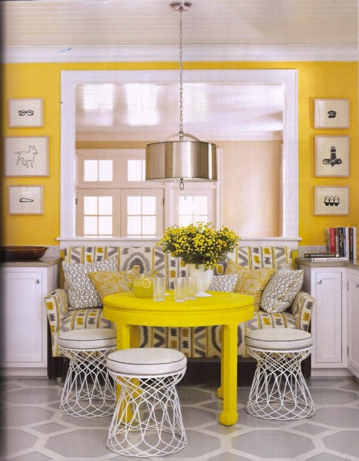 Küche-gelbes-Interieur-süßer-Tisch-kleine-Couch-buntes-Muster-graphische-Kissen-Gläser-gelbe-Blumen-Hocker