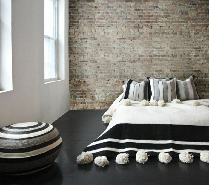 Schlafzimmer-Ziegelwände-minimalistische-Einrichtung-marokkanischer-Pom-Pom-Bettüberwurf-schwarz-weiß-grau
