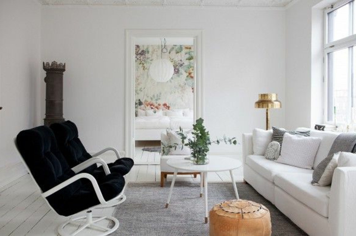Wohnzimmer-skandinavischer-EInrichtungsstil-schwarz-weiß-bequemes-Sofa-runder-Couchtisch-weiß-Hocker-schwarze-Sessel