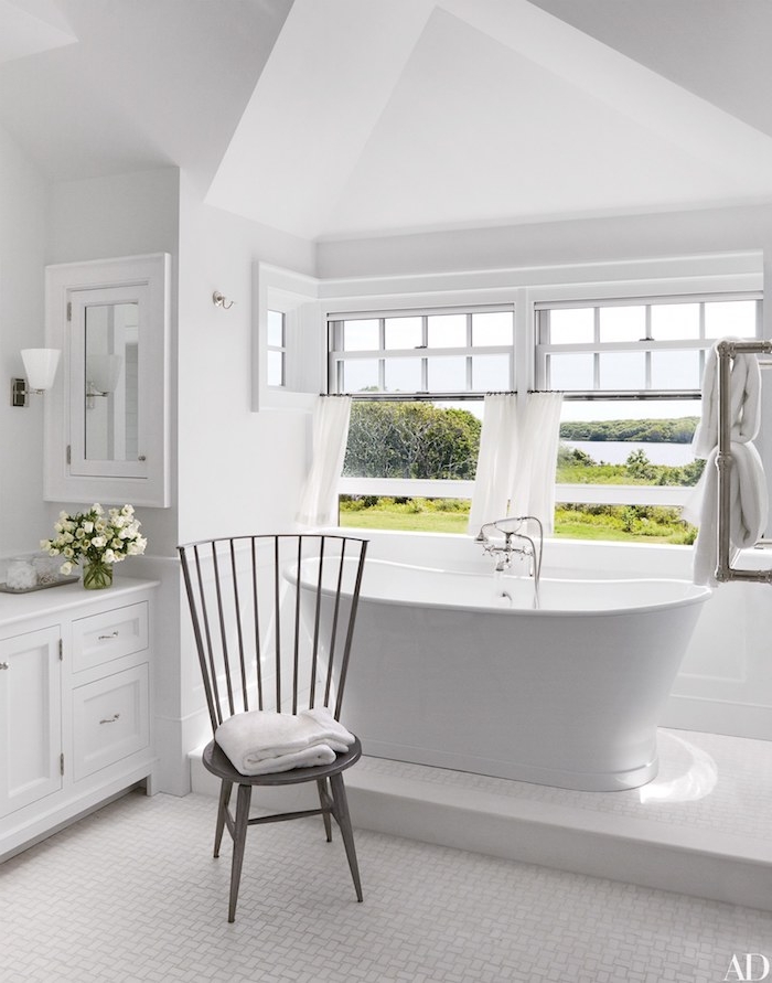 Badezimmer in Weiß gestalten, Badewanne aus Keramik und Holzmöbel, großes Fenster