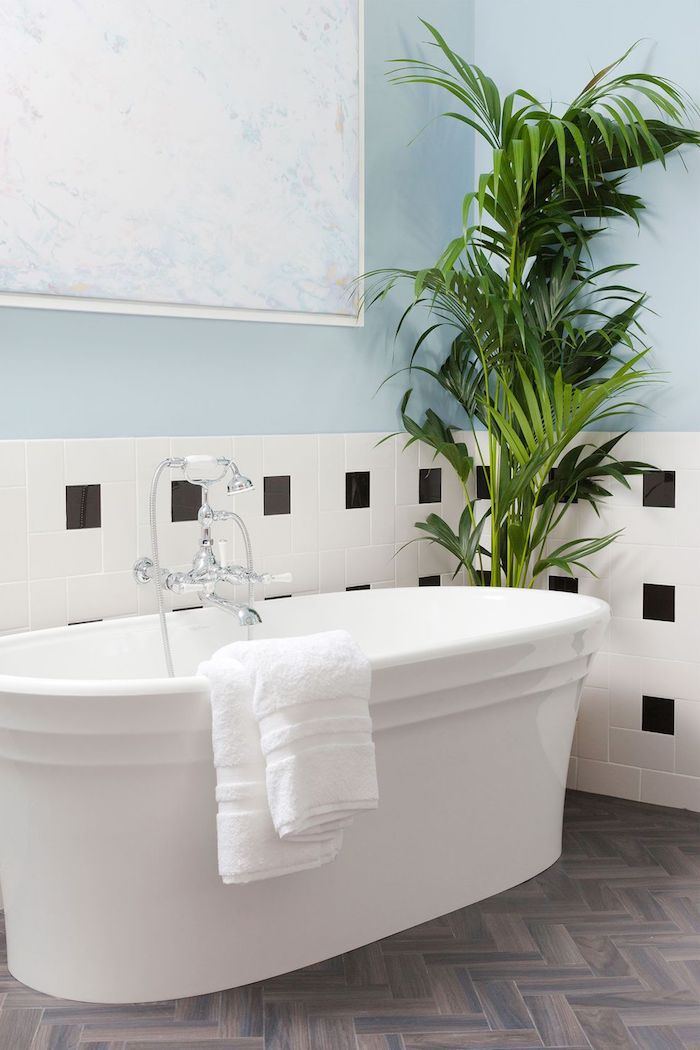 Moderne Bäder, weiße Badewanne aus Keramik, Parkett und Fliesen, große Grünpflanze 
