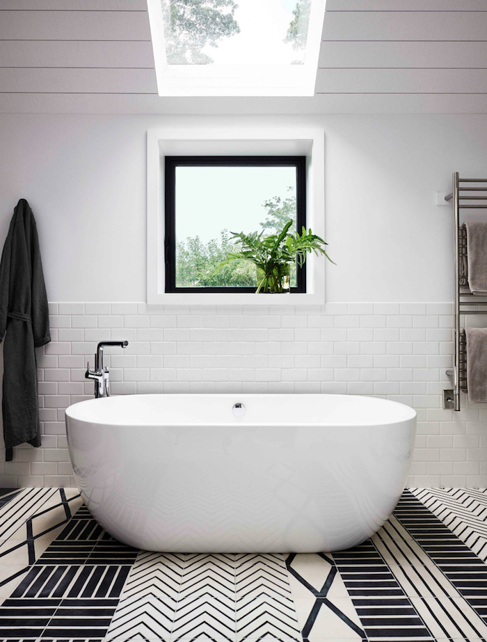 Minimalistische Badeinrichtung, weiße Badewanne aus Keramik, weiße Fliesen
