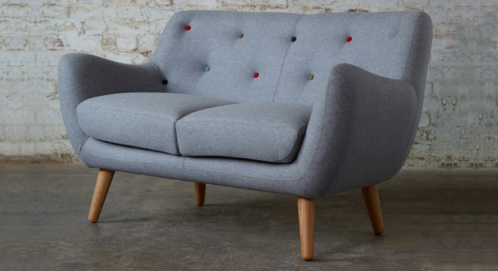 graues-kleines-Sofa-Textil-bunte-Knöpfen-Ziegelwand