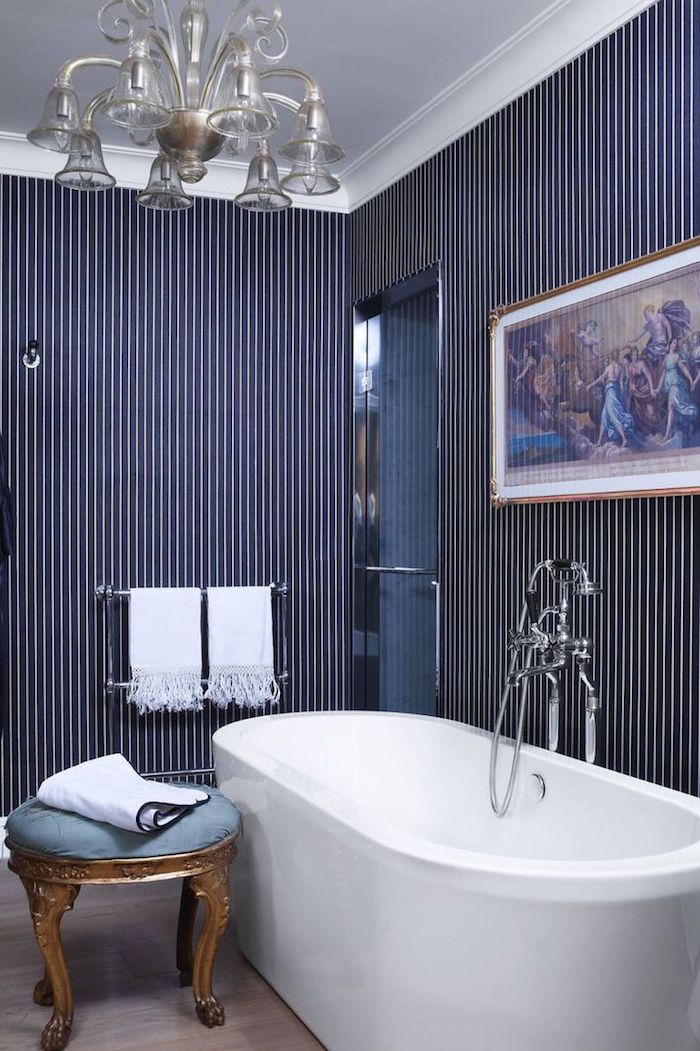 Badezimmer modern gestalten, weiße Badewanne aus Keramik, verspielter Kronleuchter, Wandgestaltung weiße und dunkelblaue Streifen 