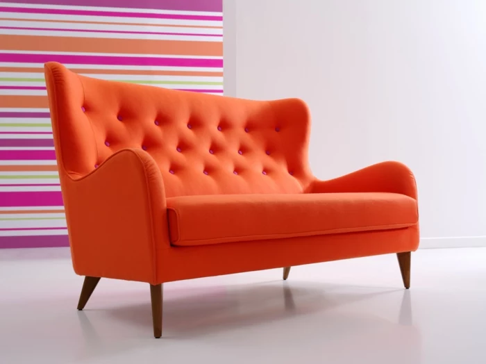 wunderschönes-orange-Sofa-Textil-rosa-Knöpfen-gestreifte-Wand-grelle-Farben