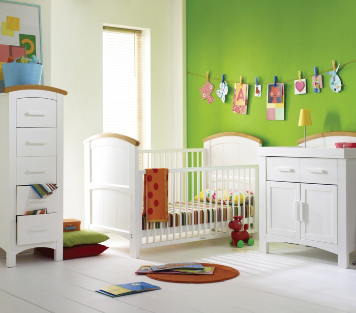Kinderzimmer-frische-grüne-Wände-lustige-Wanddekoration-Babybett-Schrank-Schubladen-weiße-Möbel-Spielzeuge