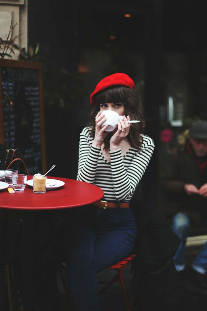 Paris-klassisches-Bild-Mädchen-Café-rote-französische-mütze-Kaffeetasse-Zigarette-roter-Tisch