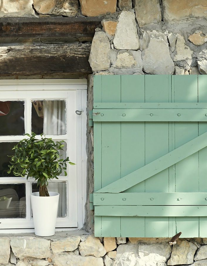 Steinwand-kleines-Fenster-weiße-Fensterrahmen-Topfpflanze-Fensterladen-Holz-frische-grüne-Farbe