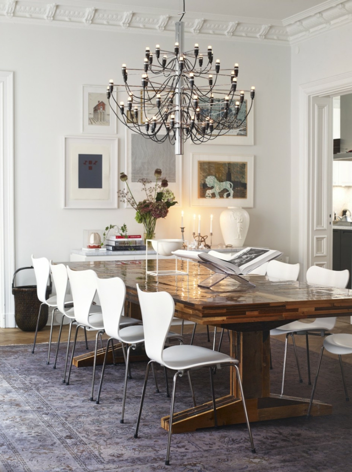 modernes-Interieur-weiße-Designer-Stühle-rustikaler-Tisch-großartiger-Kronleuchter-Landhausstil