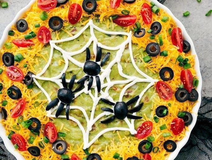 vorspeisen ideen spinnennetz avocado dip mit käse tomaten schwarze oliven dekoration schwarze spinnen halloween buffet