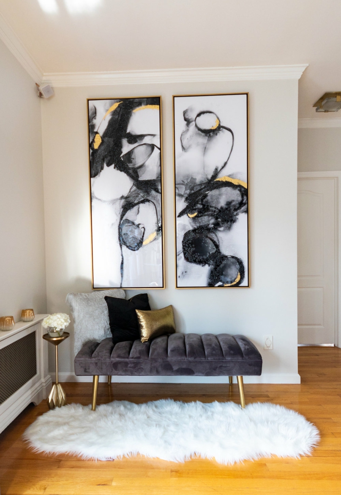 Leinwandbilder Wohnzimmer, zwei gemalte Bilder in schwarz weiß mit gelbem Motiv, Liege in dunkelgrau mit Kissen, flauschiger Teppich