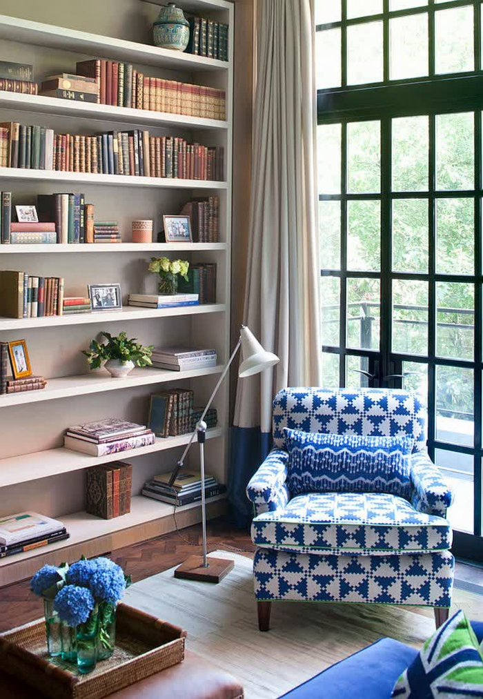 gemütliches-Wohnzimmer-große-Bücherwand-lila-Blumen-Leselampe-schöner-Sessel