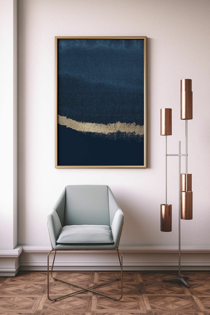 gemalte Bilder in blau und gold, modische Kunst, Bild aufgehängt an rosa Wand, Sessel in grau-grün, interessante Lampe