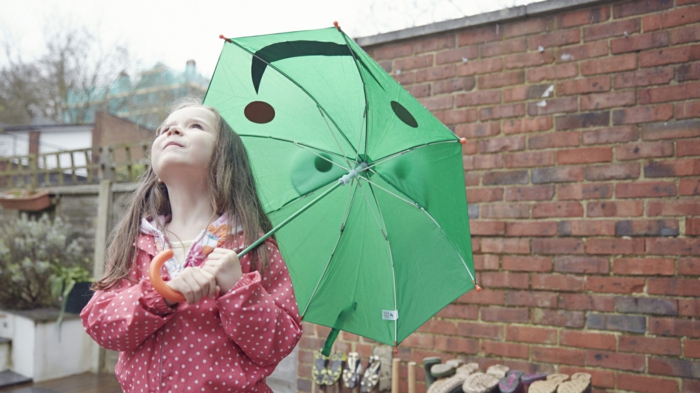 kleines-Mädchen-grüner-kinderregenschirm-regnerischer-Tag