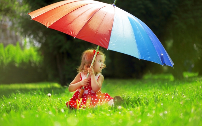 kleines-Mädchen-im-Gras-mit-großem-regenschirm