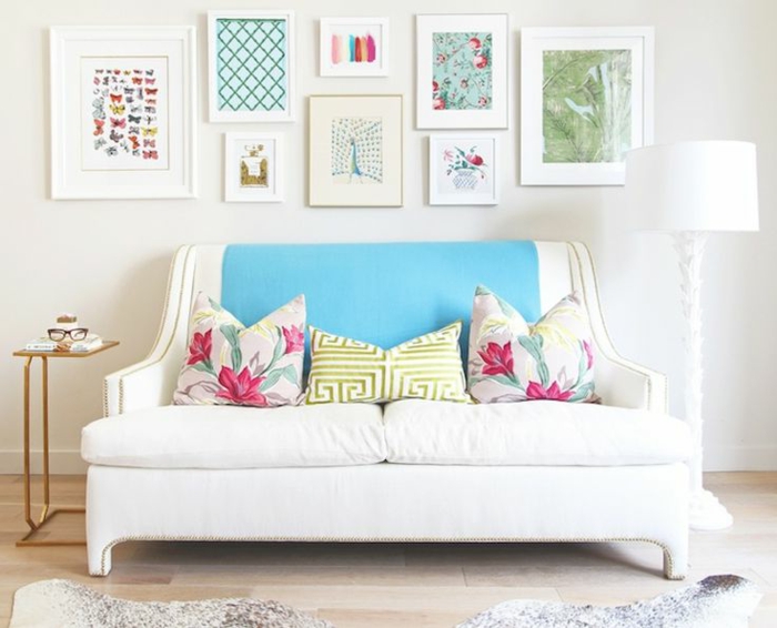 kreatives-Interieur-weißes-Sofa-Kissen-florale-Motive-artistische-Wandbilder-schöne-elegante-Leselampe