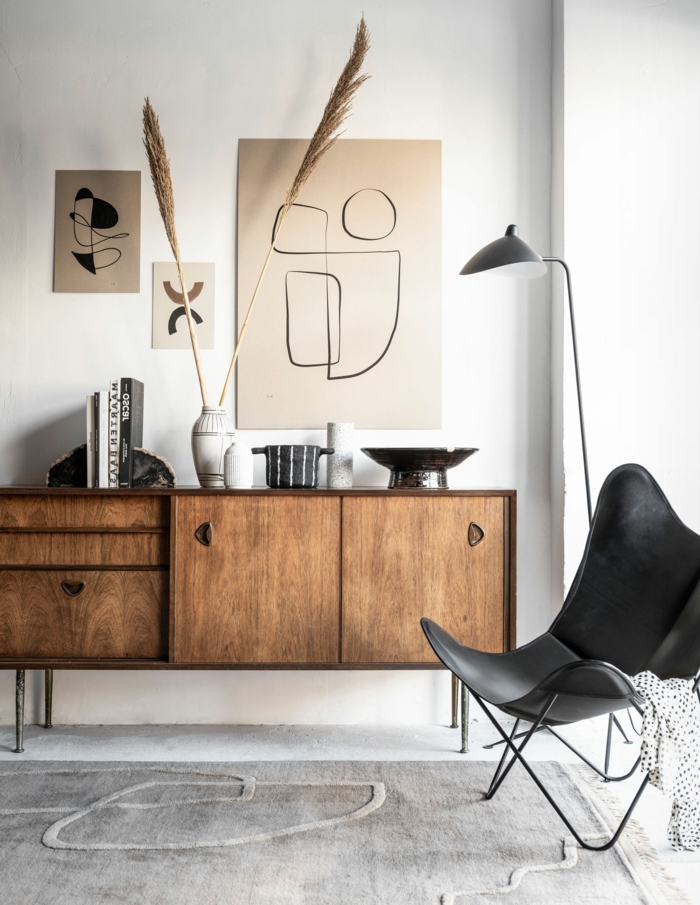 Moderne Inneneinrichtung mit Kommode aus Holz, Linienzeichnungen moderne Bilder, schwarzer Stuhl,