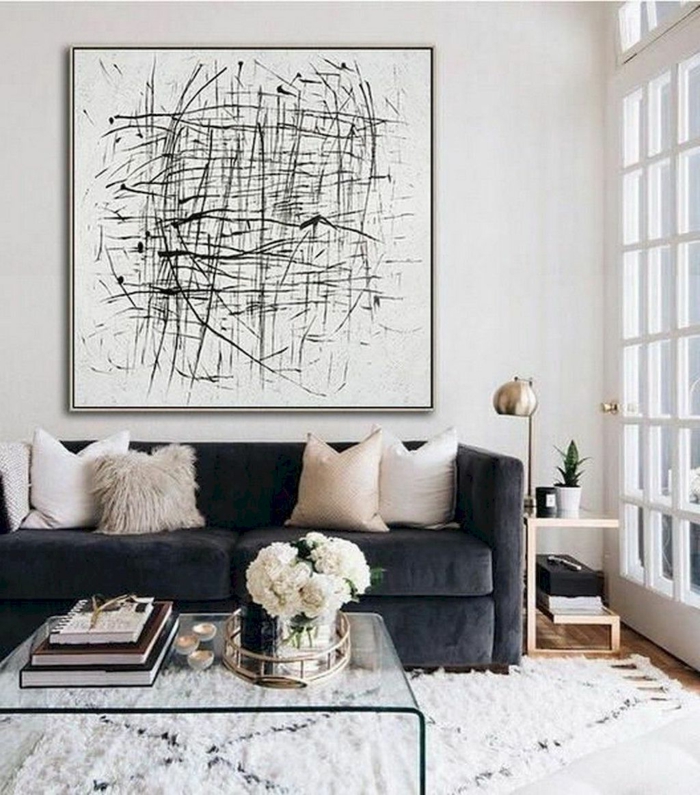 Bilder Wohnzimmer abstrakt, Couch in dunkler Farbe und helle Kissen, Tisch aus Glas mit Blumen obendrauf, artistisches Gemälde