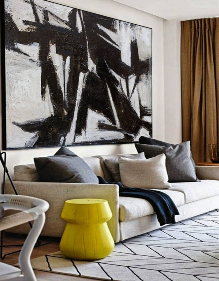Wandbilder XXL, Couch in beige mit Kissen, kleiner Tisch in gelb, große Wandbilder in schwarz und weiß