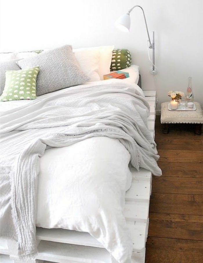 weiße-Schlafzimmer-Gestaltung-Europaletten-Bett-weiße-Bettwäsche-grüne-Kissen-Leselampe