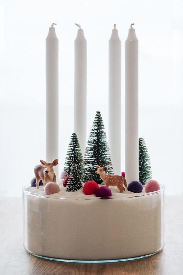 Adventskranz einfach und schnell zum Nachmachen, vier weiße Kerzen in Schüssel mit Sand, kleine Christbäumchen, Rehe und bunte Kugeln