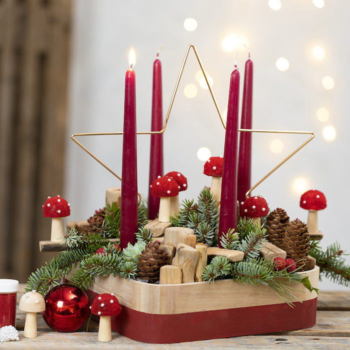 DIY Adventskranz Ideen, vier rote Kerzen in Holzständer, großer Stern aus Metall, Tannenzweige und Zapfen