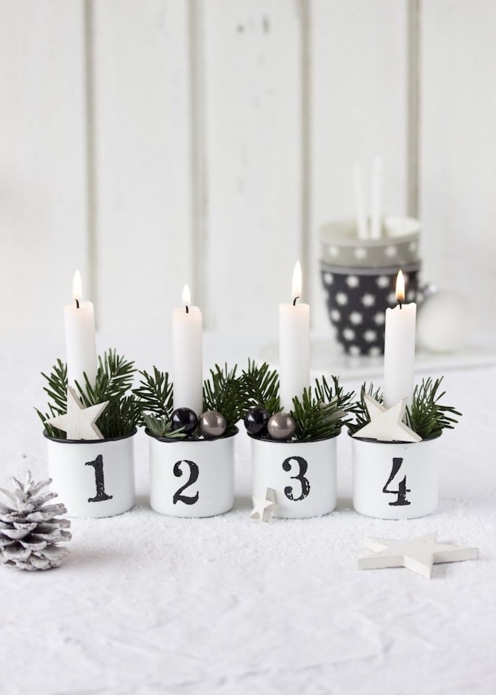 Alternative zum klassischen Adventskranz, weiße Kerzen in kleinen Tassen mit Nummern, verziert mit Tannenzweigen und kleinen Christbaumanhängern 