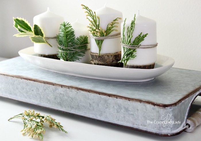 Idee für selbstgemachten Adventskranz, weiße Kerzen mit Tannenzweigen und Blättern von Grünpflanzen dekorieren
