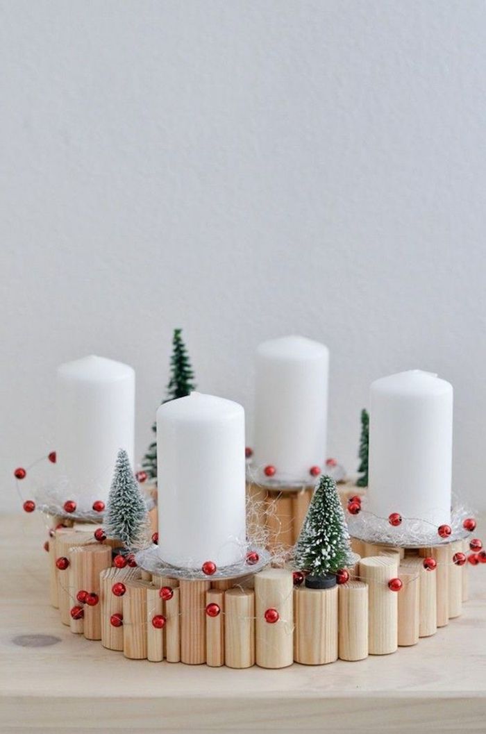 Adventskranz selber basteln, vier weiße Kerzen auf Ständer aus Holz, kleine Christbäumchen und rote Kugeln 