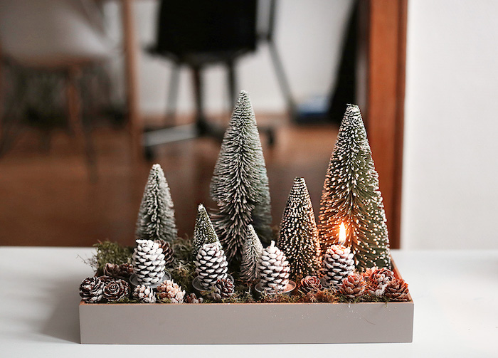 Kreative Idee für selbstgemachten Adventskranz, vier Kerzen in Form von Tannenzapfen, kleine Christbäumchen mit künstlichem Schnee