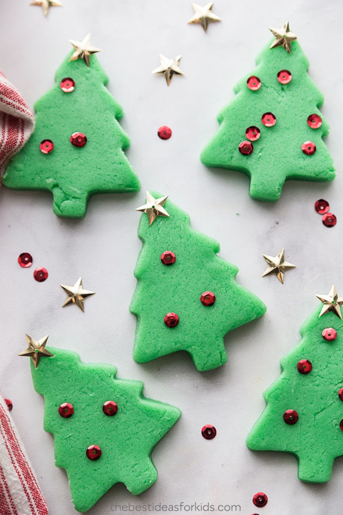Kleine Weihnachtsbäume aus grüner Knetemasse ausstechen, mit roten Pailletten und kleinen Sternen verzieren