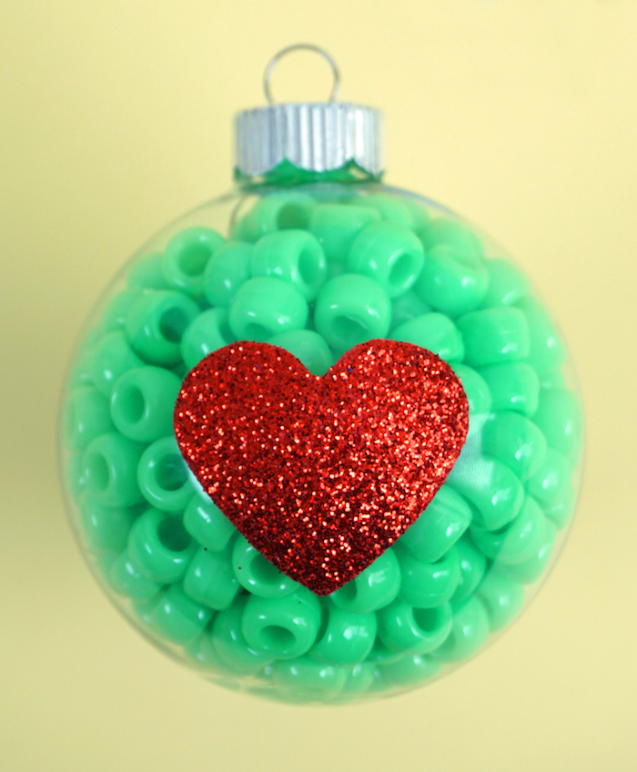 Durchsichtige Christbaumkugel aus Glas mit grünen Perlen füllen, rotes Glitzer Herz aufkleben 