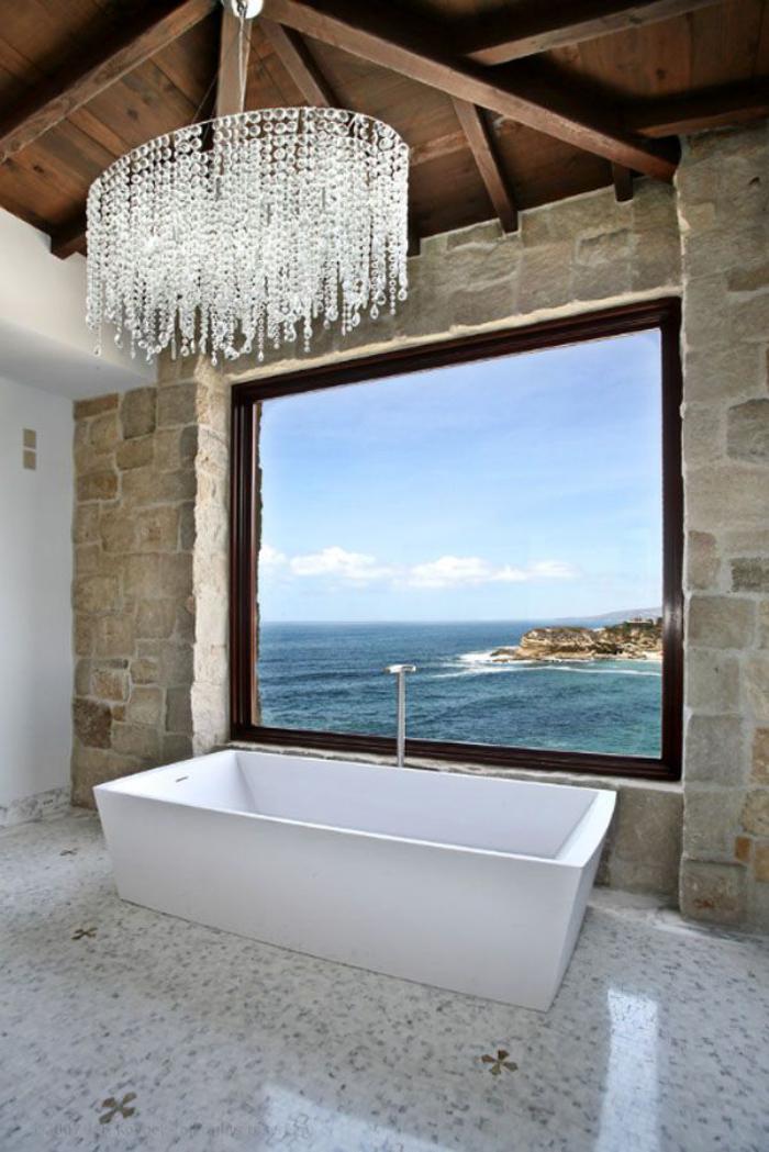 Badezimmer-mit-schönem-Ausblick-in-rustikalem-Stil-Steinwand-hölzerne-Zimmerdecke-wundervoller-Kristall-Kronleuchter