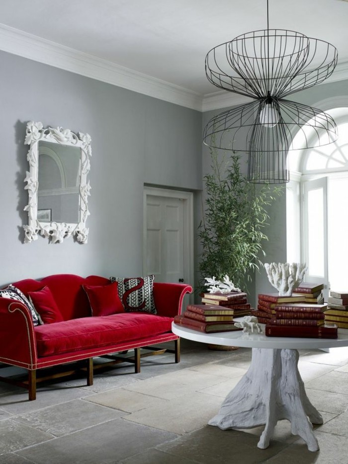 Designer-Wohnung-feine-Möbel-interessante-Leuchte-Spiegelrahmen-mit-Ornamenten-rotes-Sofa-aus-Samt