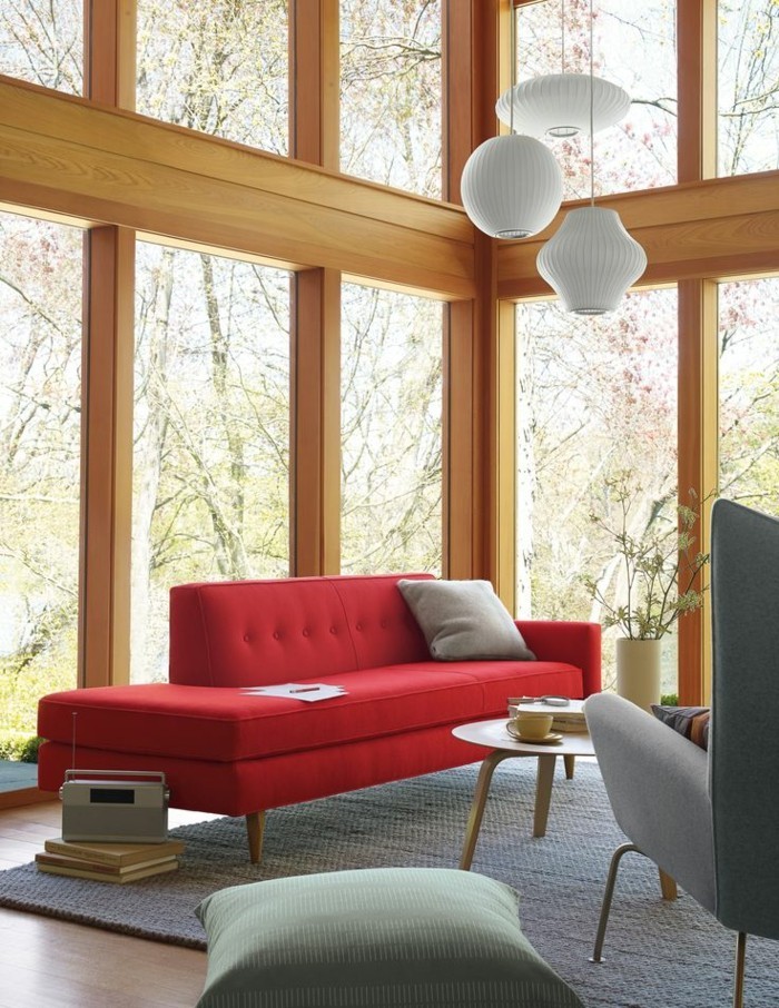 Ferienhaus-große-Fenster-grauer-Sessel-rote-Couch-mit-modernem-Design