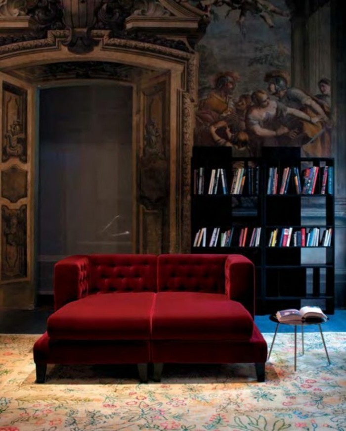 aristokatische-Wohnung-Bücherregale-Wandgestaltung-mit-historischen-Motiven-rote-Couch-aus-Samt